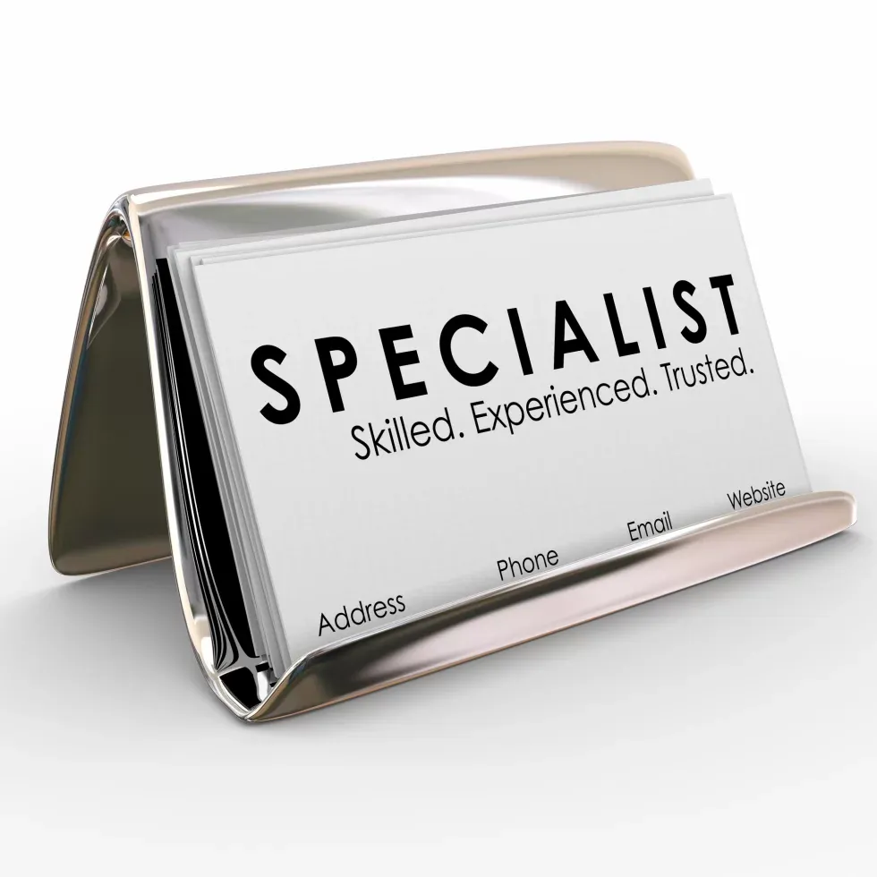 A sleek, metallic business card holder displays a card labeled "SPECIALIST" with the words "Skilled. Experienced. Trusted." Keywords include address, phone, email, website.