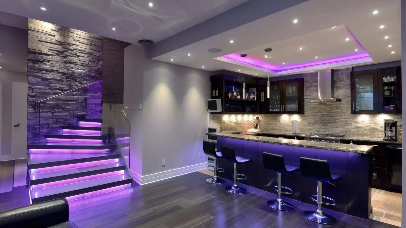 Modern kitchen with a sleek bar area, illuminated by purple LED lighting. Features stone accent wall, glass staircase, and black bar stools, conveying a stylish ambiance.
