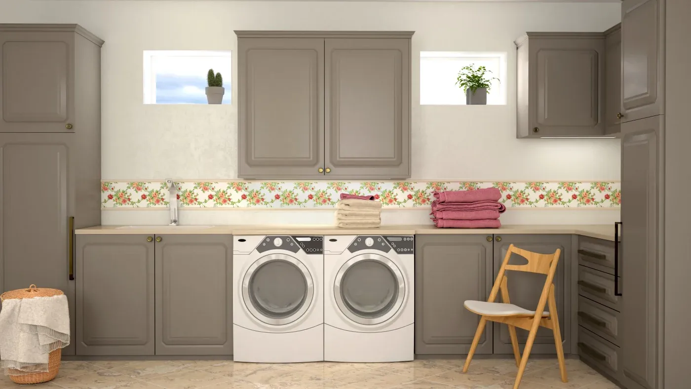 A laundry room with gray cabinets, two windows, and a floral backsplash. Two washers, folded towels, a wicker basket, and a wooden chair are visible.