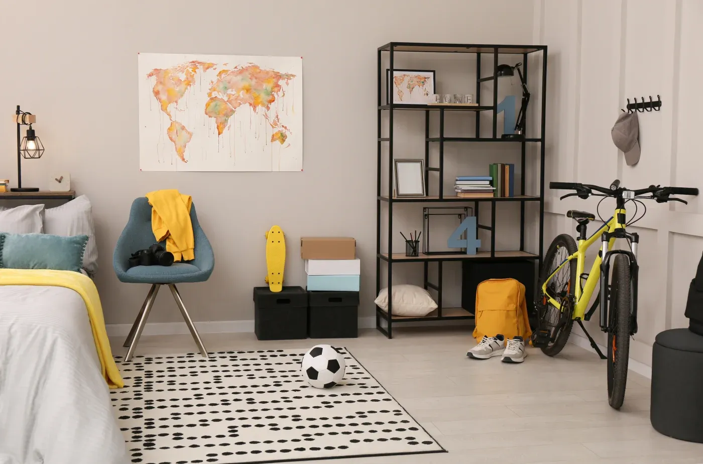 A modern bedroom with a cozy vibe features a world map on the wall, a blue chair with a yellow blanket, a shelf with books, and a bicycle. A soccer ball and skateboard add a sporty touch.