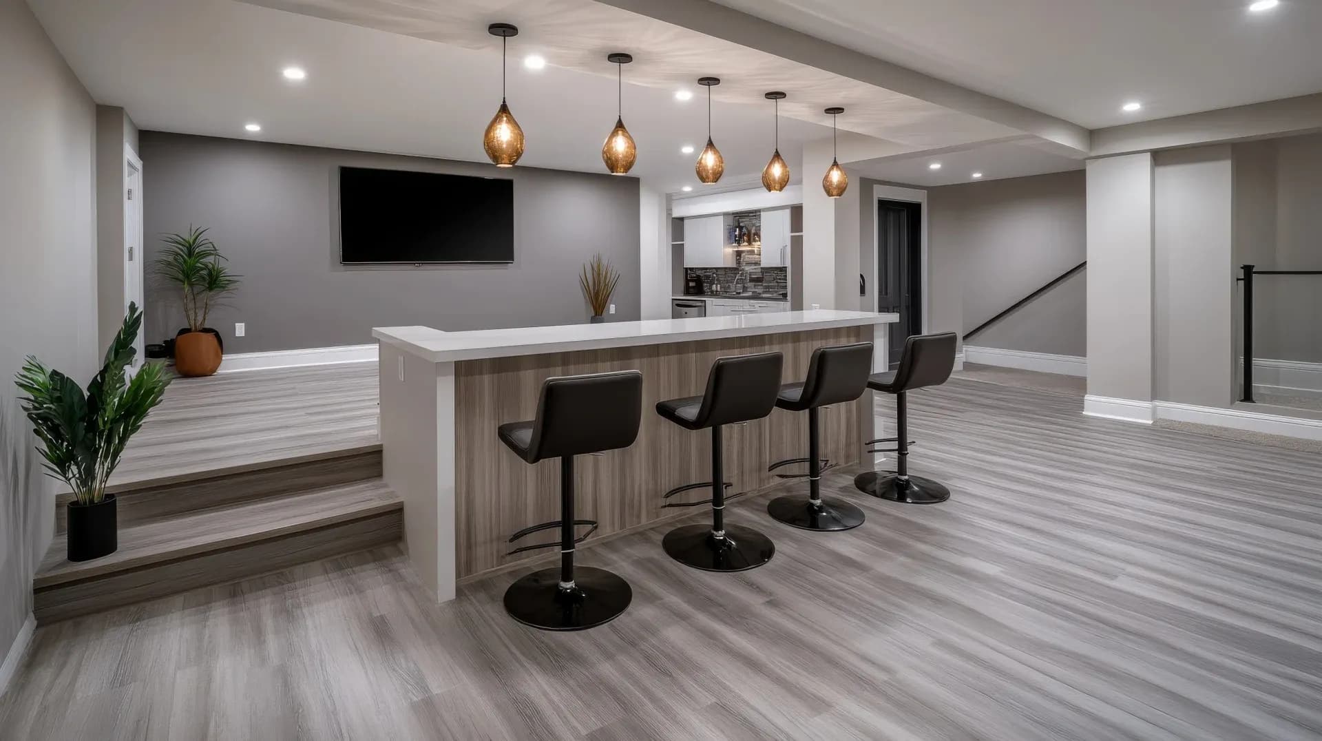 A modern basement features a sleek bar with four black stools, pendant lights, and a TV. Neutral tones, plants, and wood floors add warmth.