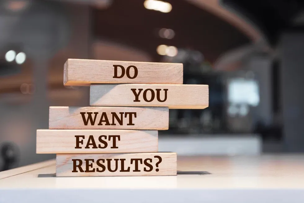 Wooden blocks stacked ask, "Do you want fast results?" The background is a blurred office setting, conveying a sense of urgency and motivation.