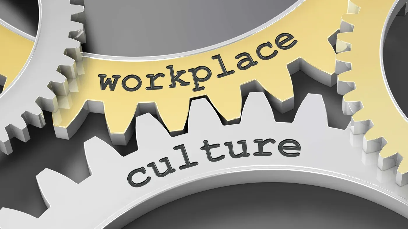 Interlocking silver and gold gears with the words "workplace" and "culture" engraved, symbolizing interconnectedness and synergy in corporate environments.