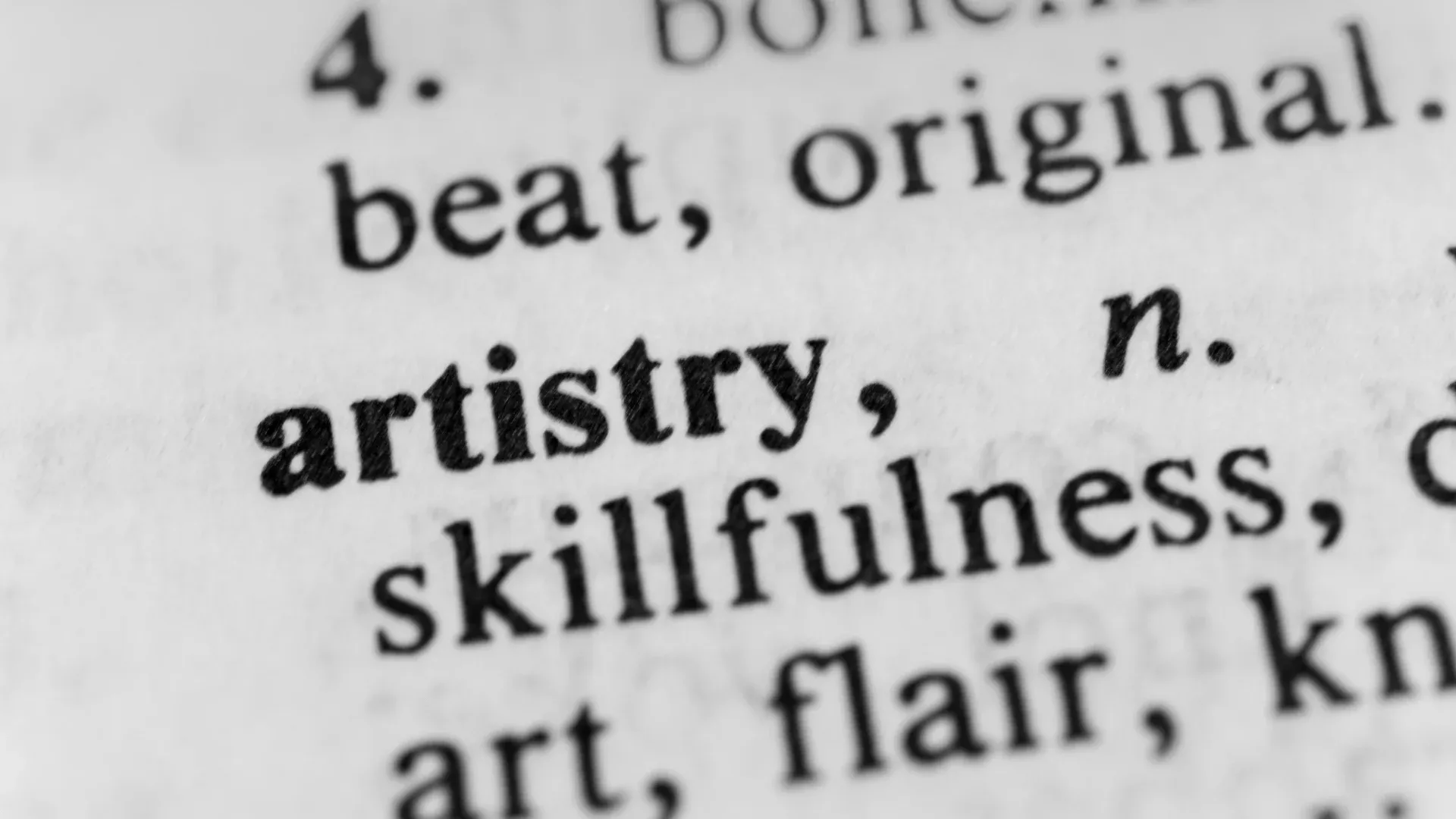 Close-up of a dictionary page showing the word "artistry" in bold. The text is sharp, conveying precision and focus on creativity and skill.