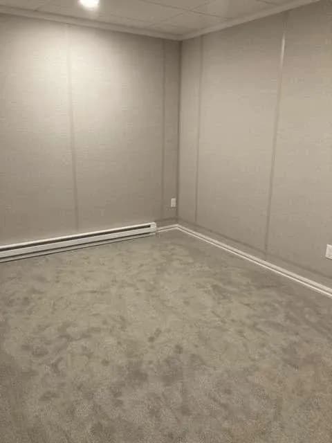 Empty room with gray carpet, beige walls, baseboard trim, and recessed ceiling light