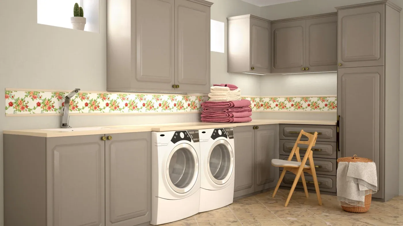 A tidy laundry room with two washing machines, beige cabinets, floral wallpaper, folded towels, a wooden chair, and a wicker basket exudes a cozy vibe.