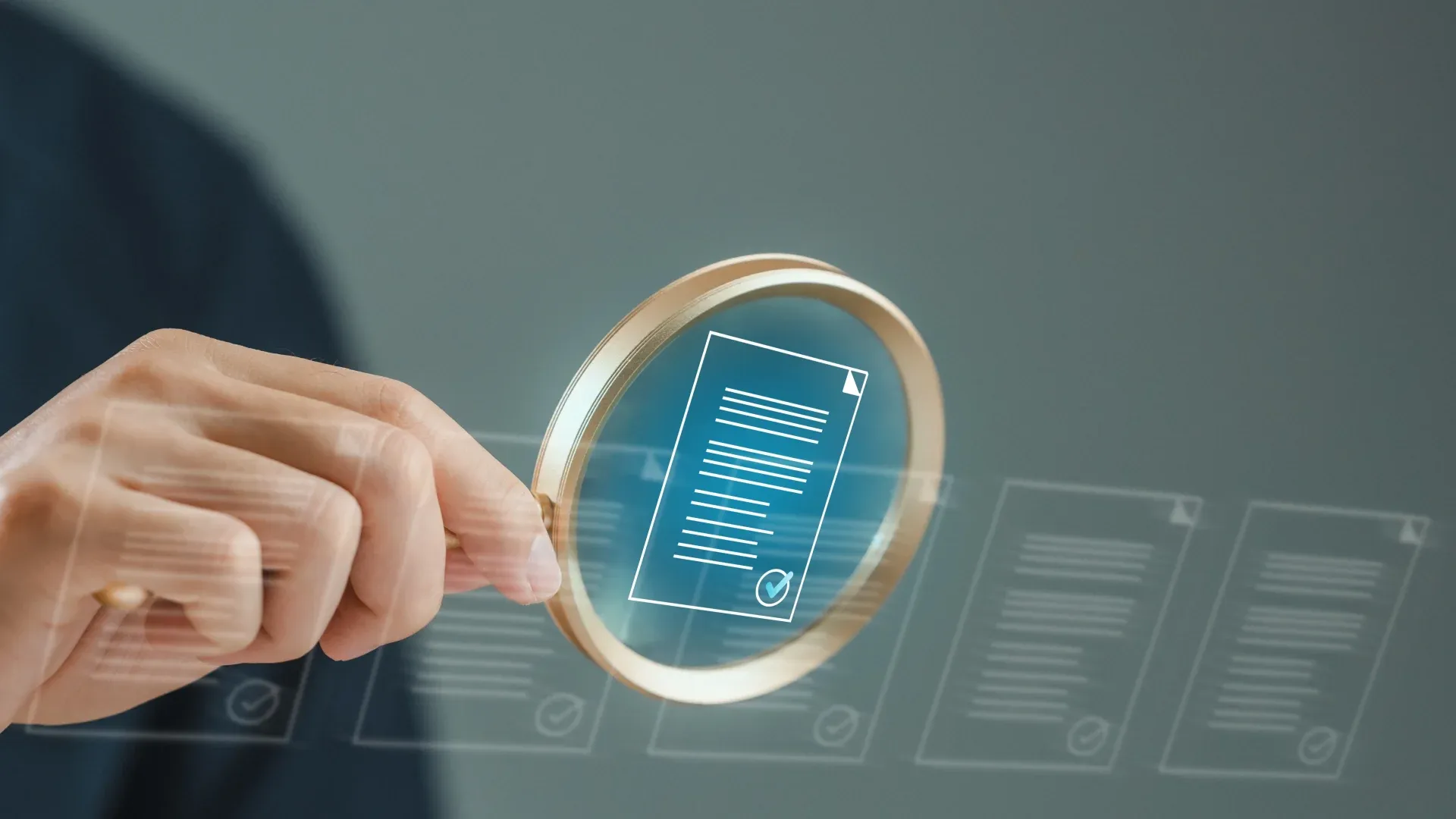 A hand holds a magnifying glass over a digital document icon, highlighted among other semi-transparent documents on a blurred gray background.