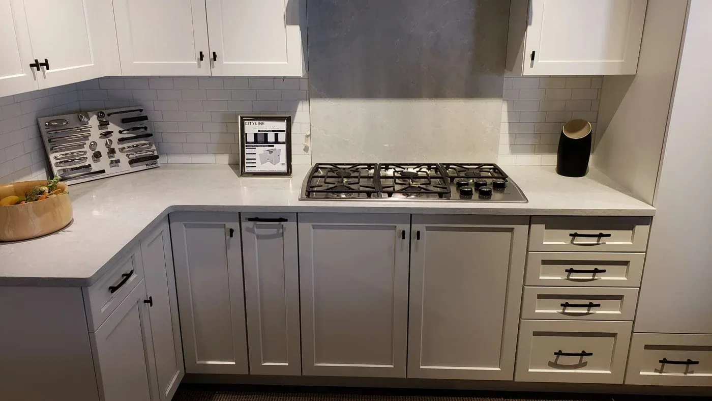 Modern kitchen with white cabinets, subway tile backsplash, and stainless steel gas stove. Countertops feature a fruit bowl and decor.