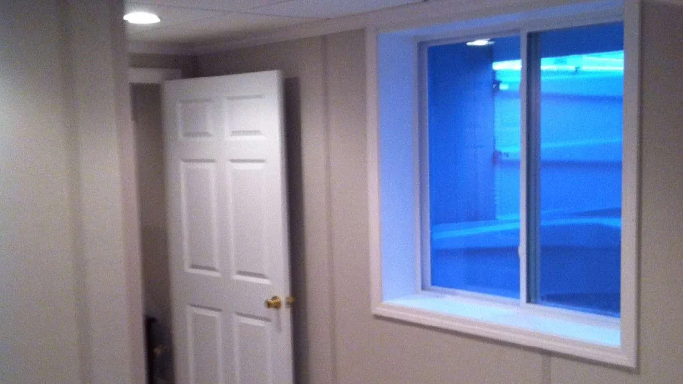 A dimly lit room with beige walls and a partially open white door. A window on the right casts a soft blue light, creating a calm, serene atmosphere.
