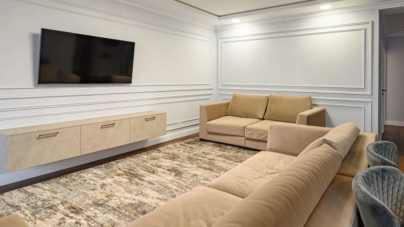 Modern minimalist living room with beige sofas, a wall-mounted TV, textured area rug, and sleek floating cabinet. Neutral tones create a calm ambiance.